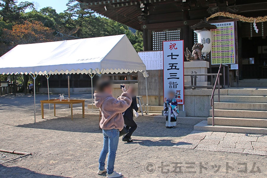 吉備津彦神社 拝殿前の「祝七五三詣」の看板で記念撮影の様子